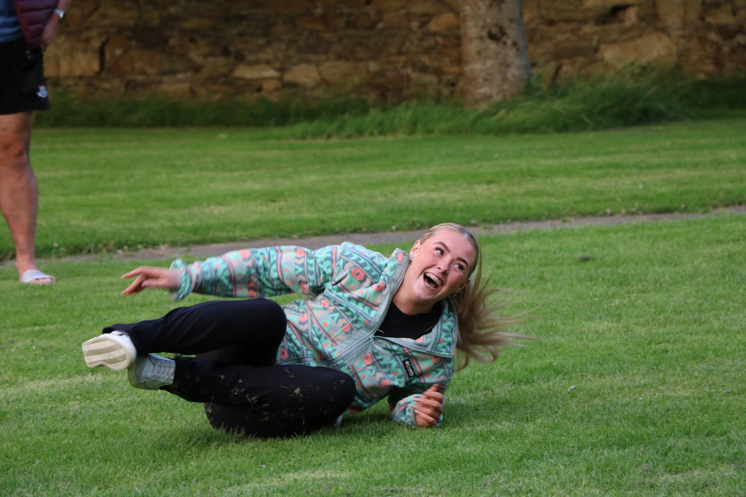 An ILE student laughing as she tumbles on the grass