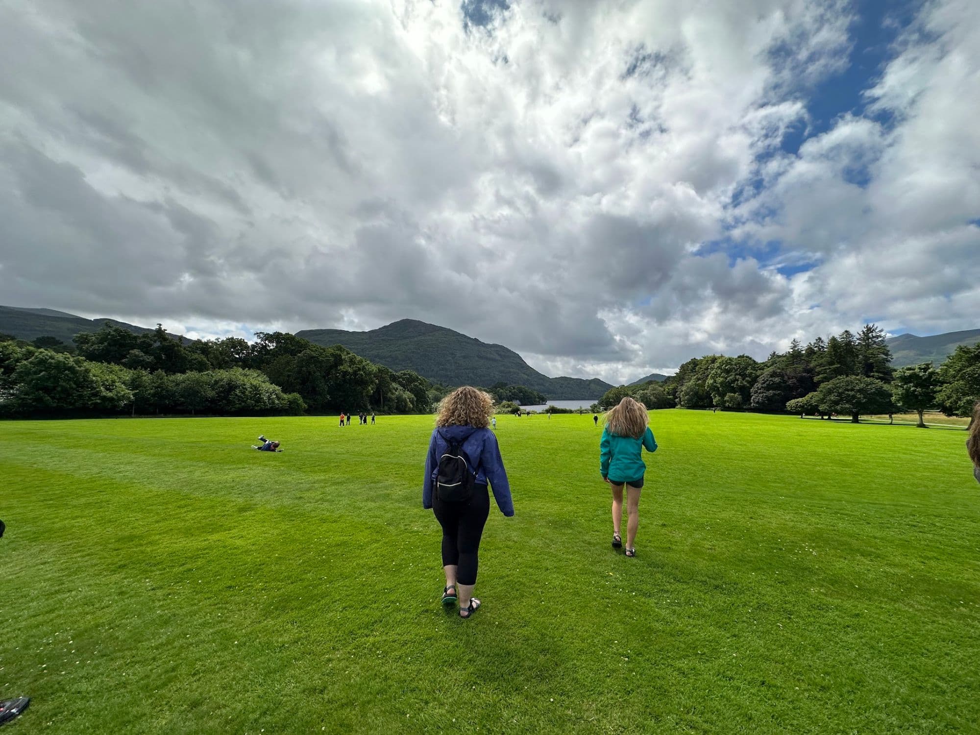 Two ILE students walking across a lawn toward a lake and mountains in Ireland